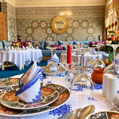 café maure de l'hôtel avec petites tables rondes et un mur décoré avec du carrelage orientale