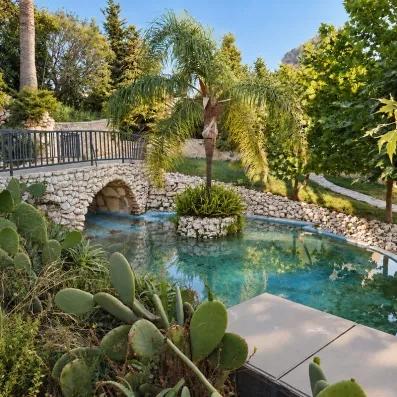 Jardin extérieur de l'hôtel avec fleuve et petit pont.