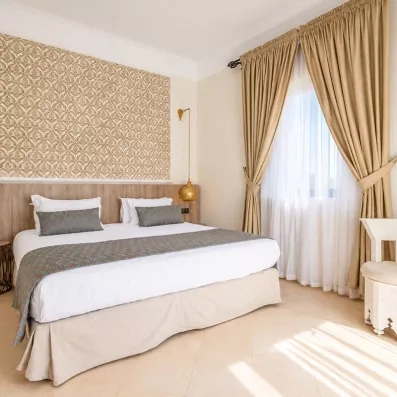 lit double, avec lampadaire suspendus avec une fenêtre décorée de rideaux en voiles blancs et beige 