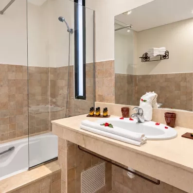 salle de bain avec lavabo intégré et un miroir juste en dessus et une baignoire avec vitre et des serviettes