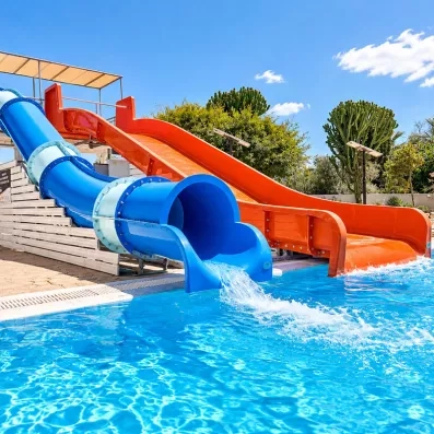 piscine de l'hôtel avec deux toboggans un couvert bleu et blanc et un orange découvert, ciel bleu sans un nuage