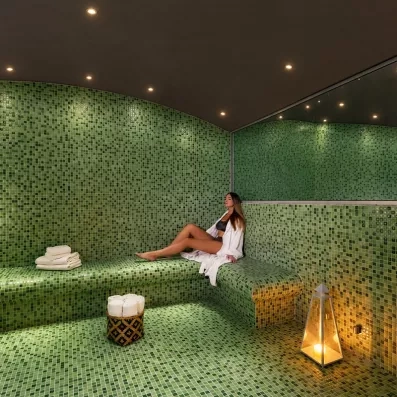 Hammam vert, femme qui profite du hammam, grand miroir en hauteur, serviettes, lampe