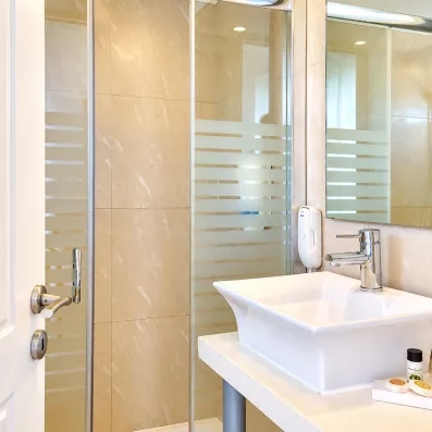 salle de bain avec lavabo en marbre blanc et un miroir accroché 