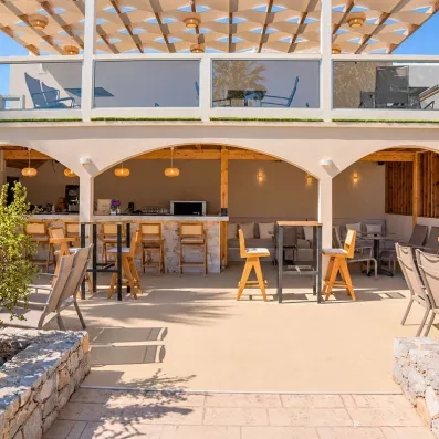 restaurant de la plage, tables carrées en bois, chaises marrons, luminaires en cordes, vue mer