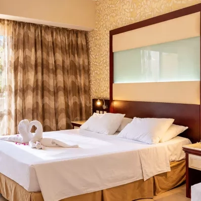 chambre avec un lit double standard en blanc et une porte fenêtre qui mène vers la terrasse 