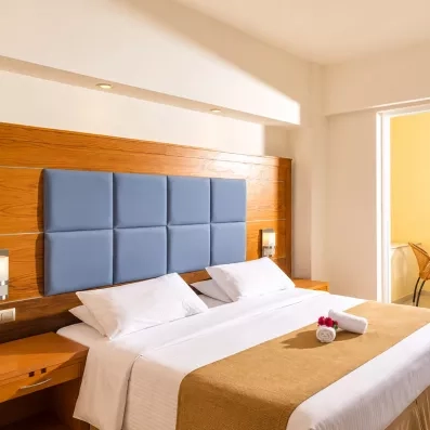 chambre avec un lit double standard en blanc et une porte fenêtre qui mène vers la terrasse vue sur mer