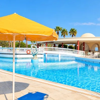 piscine avec un pont vers le bar de l'hôtel  parasol jaune