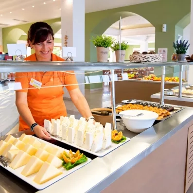 serveuse posant sur le buffet un plateau de fromages au restaurant de l'hôtel