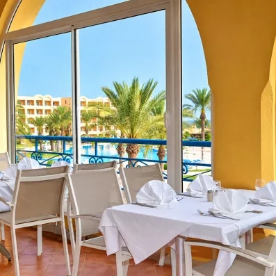 Table dressée du restaurant avec vue panoramique sur la piscine et la mer à l'Hôtel Nour Palace Mahdia