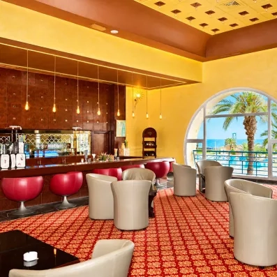 Bar lounge élégant de l'hôtel Nour Palace Mahdia avec baies vitrées face aux jardins