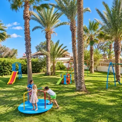 Aire de jeux extérieure pour enfants sous les palmiers au Mondi Club Nozha Beach.