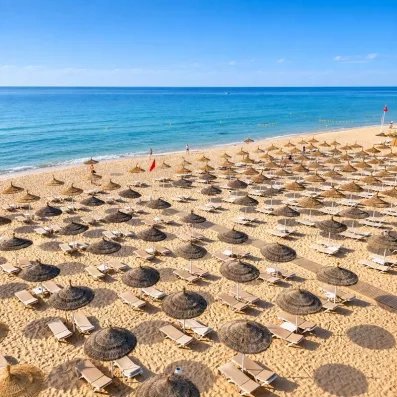 Plage privée de sable fin aménagée de parasols en paille au Mondi Club Nozha Beach à Hammamet