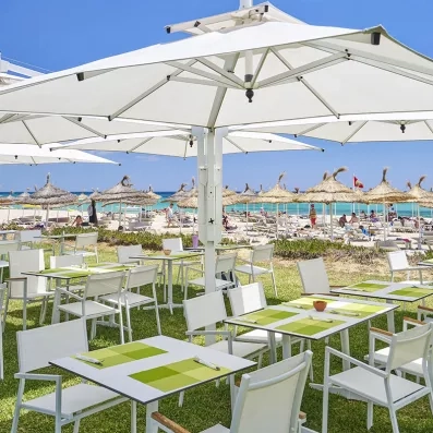 Terrasse extérieure du restaurant avec tables dressées sous de grands parasols au Mondi Club Nozha Beach à Hammamet.