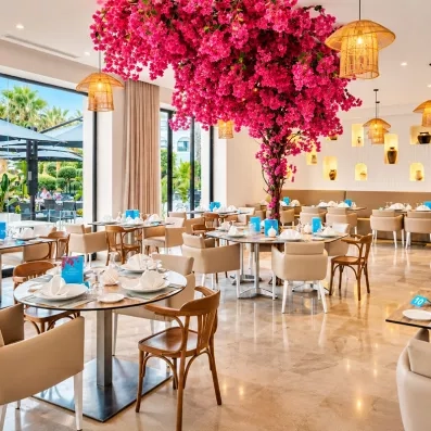 Salle de restaurant intérieure du Mondi Club Nozha Beach décorée d'un grand bougainvillier rose et de suspensions en bambou.