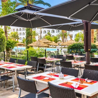 Terrasse du restaurant de l'hôtel Mondi Club Nozha Beach avec vue sur le jardin et la piscine à Hammamet.