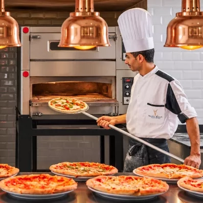 Chef préparant des pizzas au four à pierre dans le restaurant buffet du Mondi Club Nozha Beach Hammamet.