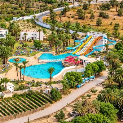 Vue aérienne du Mondi Club One Resort Jockey à Monastir en Tunisie, avec ses grandes piscines, ses toboggans aquatiques et ses palmiers.