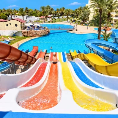 Vue depuis le haut d'un toboggan aquatique multicolore avec enfant glissant vers la piscine du Mondi Club One Resort Jockey.