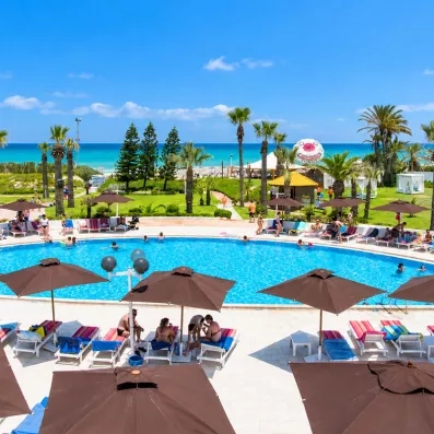 Vue panoramique sur la piscine, le jardin de palmiers et la plage du Mondi Club One Resort Jockey Monastir.