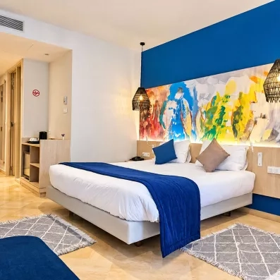 Chambre double moderne de l'hôtel Mondi Club One Resort Jockey à Monastir en Tunisie avec fresque colorée et chemin de lit bleu