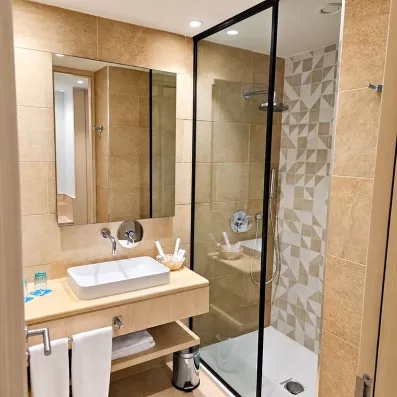 Salle de bains moderne avec douche à l'italienne et vasque posée au Mondi Club One Resort Jockey Monastir