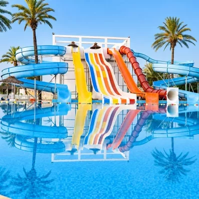Parc aquatique du Mondi Club One Resort Jockey à Monastir avec des toboggans multicolores se reflétant dans une piscine turquoise.