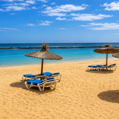 Une vue paradisiaque d'une plage de sable doré bordée par une mer turquoise sous un ciel bleu.