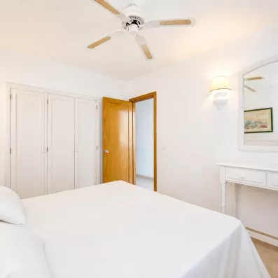 Un plan large d'une chambre avec un lit double, une commode et une porte entrouverte.