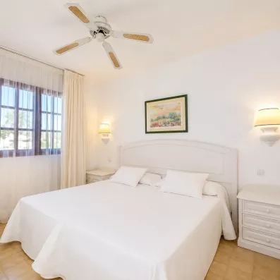 Une chambre d'hôtel minimaliste avec un lit double fait de draps blancs.