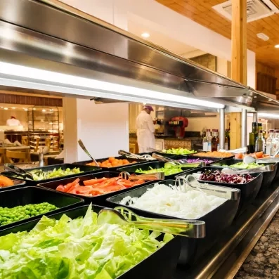 Un buffet de salades propose une variété de légumes frais, sous un éclairage suspendu.