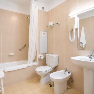 Une salle de bain fonctionnelle avec une baignoire, un toilette et un grand miroir.