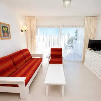 Un salon minimaliste avec un canapé-lit, un fauteuil assorti, une table basse et des baies vitrées.