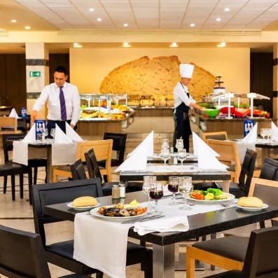 Un restaurant élégant où des serveurs préparent des tables dressées.