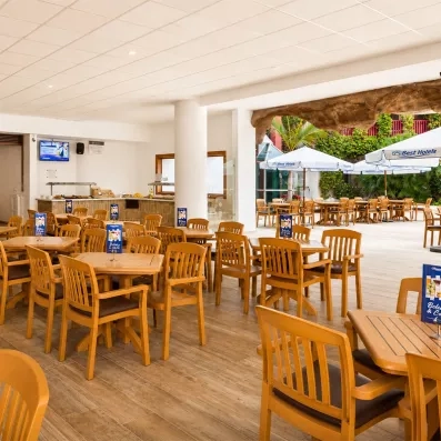 Une salle de snack-bar , équipée de mobilier en bois clair et ouverte sur l'extérieur.