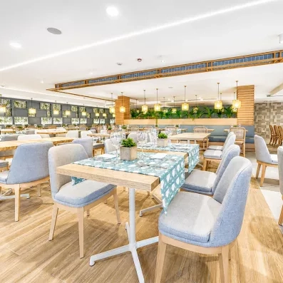 Une salle de restaurant lumineuse, avec des chaises et des tables parfaitement dressées.