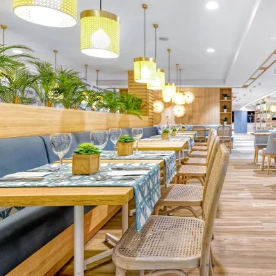 Une perspective élégante du restaurant mettant en avant des luminaires suspendus et un mobilier en bois clair.