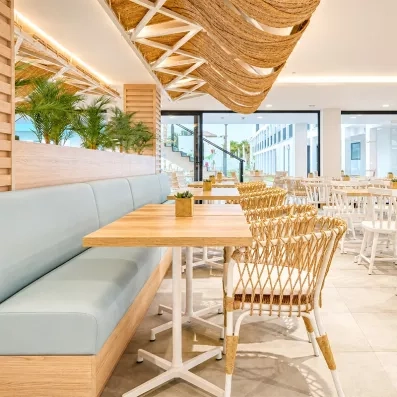 Un espace de restauration intérieur lumineux et moderne avec du mobilier en bois et des banquettes.