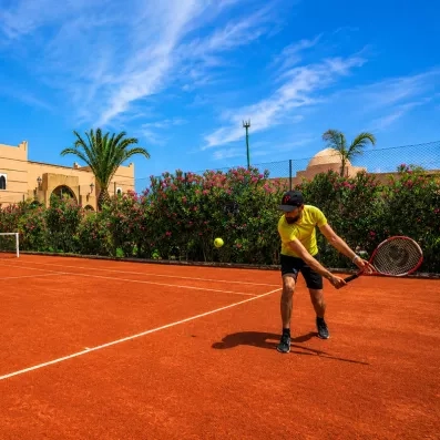 court de tennis en terre battue avec une personne tenant une raquette 