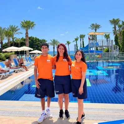 Trois animateurs posent sur la piscine en arrière plan.