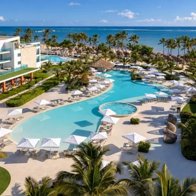 piscine près de la plage, pieds dans l'eau, palmiers et végétation importante, transats et parasols
