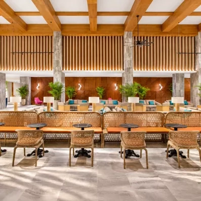salon proche de l'accueil, banquettes et chaises en osier, plantes, lampes sur les tables