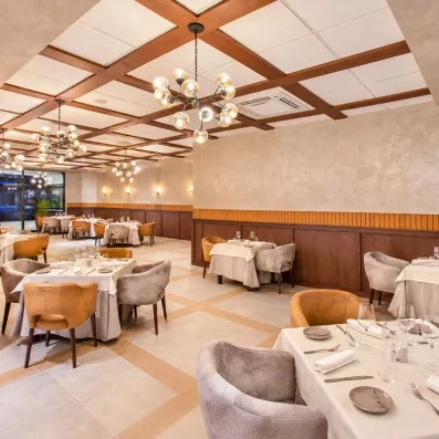 salle de restaurant avec lustres en forme de bulles, nappes blanches, verres à viin, fauteuils en velours gris et marrons