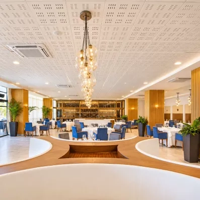 restaurants fauteuils bleus et tables rondes avec nappes blanches, lustres en forme de bulles sur toute la longueur du plafond