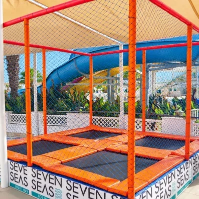 Zone de trampolines sécurisée pour enfants avec toboggan aquatique en arrière-plan au Mondi Club Seven Seas Jolie Bay.