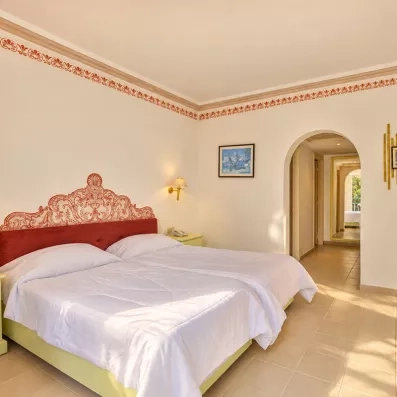Chambre double lumineuse avec tête de lit sculptée bordeaux au Mondi Club Shalimar Hammamet