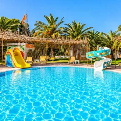 Piscine pour enfants avec toboggan aquatique et palmiers au Mondi Club Shalimar Hammamet.
