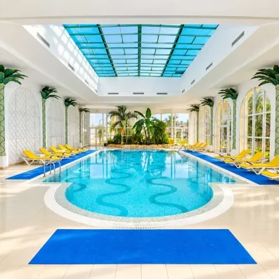 Piscine intérieure couverte avec verrière et transats au Mondi Club Shalimar Hammamet.
