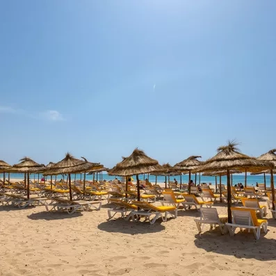 Plage de sable fin bordée de parasols en paille au Mondi Club Shalimar Hammamet