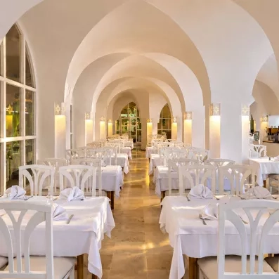 Grande salle à manger lumineuse du restaurant avec colonnes et arches blanches au Mondi Club Shalimar Hammamet