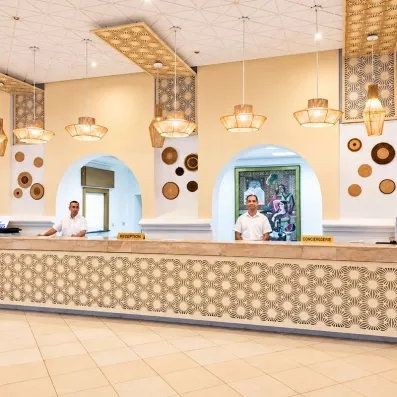 Comptoir de réception lumineux et spacieux de l'hôtel Mondi Club Shems à Monastir au design typique.